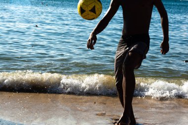 Salvador, Bahia, Brezilya - 09 Mart 2019: Salvador, Bahia 'da Ribirya plajının kenarında genç bir adamın futbol oynadığı görüldü.