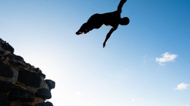 Salvador, Bahia, Brezilya - 31 Mayıs 2019: Genç adam, siluet içinde, Bahia 'nın Salvador kentindeki Porto da Barra iskelesinden atlarken görüldü..