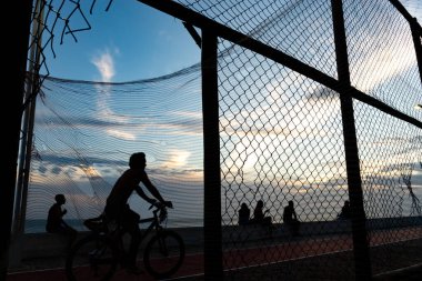 Salvador, Bahia, Brezilya - 19 Aralık 2021: İnsanlar Salvador, Bahia kentindeki Rio Vermelho plajında gün batımında gezinirken görüldü.