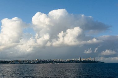 Gökyüzünde büyük beyaz bulutlar olan okyanus manzarası. Güney Amerika. Uzakta Salvador, Brezilya.