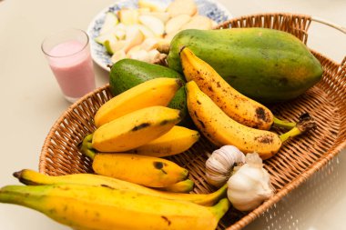 Muz, papaya ve sarımsaklı meyve kasesi. Bir fincan yoğurt ve bir kahvaltı tabağı içinde muz, elma, armut, bisküvi, peynir ve yoğurt. Sağlıklı yemek..