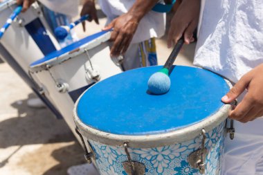 Salvador, Bahia, Brazil - December 13, 2023: Musicians from the group Filhos de Gandhy are seen playing percussion during a tribute to Santa Luzia in the city of Salvador, Bahia. clipart