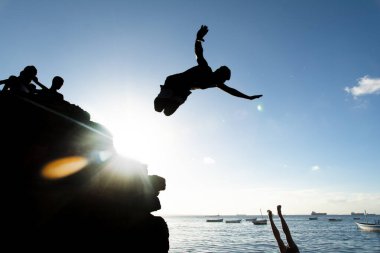 Salvador, Bahia, Brezilya - 31 Mayıs 2019: Genç adam, siluet içinde, Bahia 'nın Salvador kentindeki Porto da Barra iskelesinden atlarken görüldü..