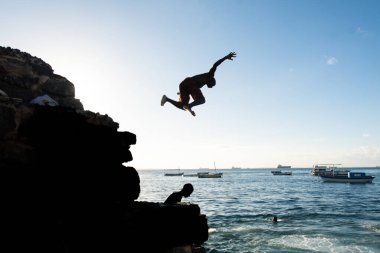 Salvador, Bahia, Brezilya - 31 Mayıs 2019: Korkusuz genç adam, siluet içinde, Salvador, Bahia 'daki Porto da Barra iskelesinden atladı.