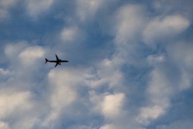 Gökyüzünde birkaç beyaz bulutlu büyük bir uçak görülür. Hava Taşımacılığı.