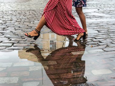 Salvador, Bahia, Brezilya - 12 Mayıs 2019: Salvador, Bahia 'nın tarihi merkezinde iki kadın yağmur suyu birikintisinin üzerinden atlarken görüldü.