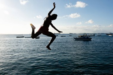 Salvador, Bahia, Brezilya - 31 Mayıs 2019: Genç adam, siluet içinde, Bahia 'nın Salvador kentindeki Porto da Barra iskelesinden atlarken görüldü..