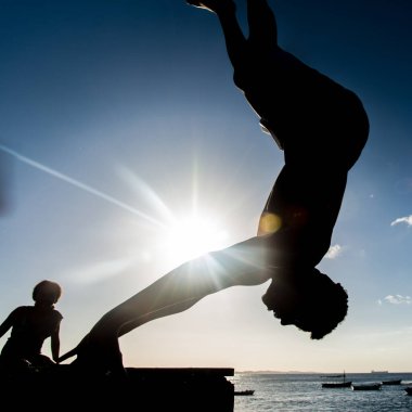 Salvador, Bahia, Brezilya - 31 Mayıs 2019: Genç yerli, siluet içinde, Bahia 'nın Salvador kentindeki Porto da Barra iskelesinden atlarken görüldü..