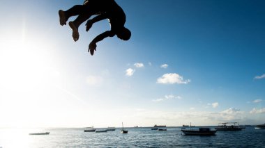 Salvador, Bahia, Brezilya - 31 Mayıs 2019: Genç adam, siluet içinde, Salvador, Bahia 'daki Porto da Barra iskelesinden atladıktan sonra havada görüldü.