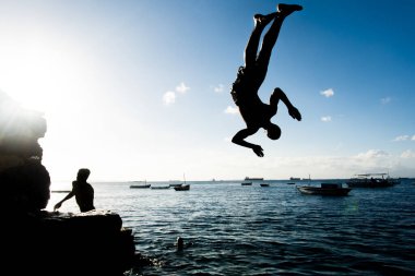 Salvador, Bahia, Brezilya - 31 Mayıs 2019: Genç adam, siluet içinde, Bahia 'nın Salvador kentindeki Porto da Barra iskelesinden atlarken görüldü..