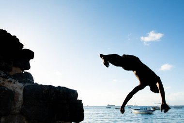 Salvador, Bahia, Brezilya - 31 Mayıs 2019: Genç yerli, siluet içinde, Bahia 'nın Salvador kentindeki Porto da Barra iskelesinden atlarken görüldü..