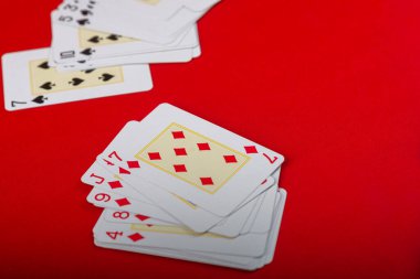 Various playing cards arranged on the board. Isolated on red background. clipart