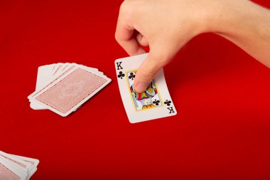 Male hand placing a playing card on the table. Board game. Isolated on red background. clipart