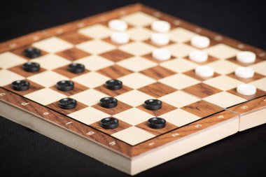 Aydınlık ve karanlık parçalı dama tahtası. Oyun konsepti. Masa oyunu. Hobi olarak. Siyah arkaplandaki bir oyun için oyun alanında dama oynatıcıları.