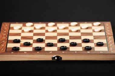Aydınlık ve karanlık parçalı dama tahtası. Oyun konsepti. Masa oyunu. Hobi olarak. Siyah arkaplandaki bir oyun için oyun alanında dama oynatıcıları.