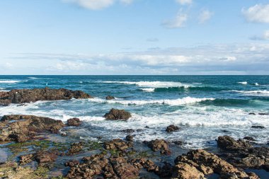 Deniz kenarında kayaları olan güzel bir sahil manzarası. Arka planda güzel mavi gökyüzü.