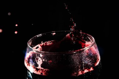 Temiz bir bardağın tepesine yakın çekim. İçi su damlalarıyla dolu bir şarap kadehi. Sıçrama Efekti. Koyu arkaplanda izole.