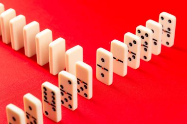 Domino etkisi başlamaya hazır. Arka arkaya akrilik parçalar. Kırmızı arkaplanda izole.