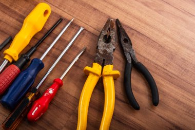 Pense, tornavida, ingiliz anahtarı ve ahşap arka planda izole edilmiş diğer aletler.