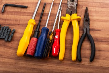 Pense, tornavida, ingiliz anahtarı ve ahşap arka planda izole edilmiş diğer aletler.