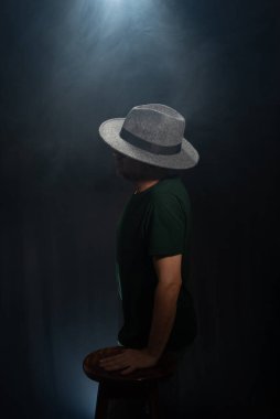 Kameraya poz veren gizemli, sakallı adam. Stüdyo portresi. Yapay dumanlı koyu yeşil arkaplan.