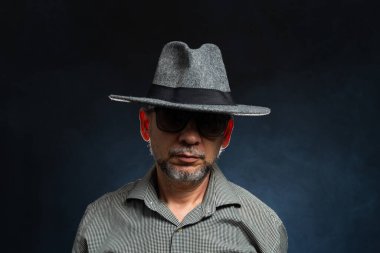 Siyah arka planda gri şapkalı, gözlüklü sakallı adam. Fotoğraf stüdyosunda..