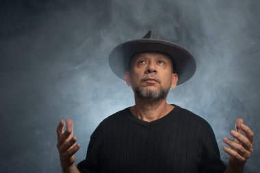 Sakallı, güneş gözlüklü ve fotoğraf için poz veren bir adamın portresi. Dumanlı arkaplana karşı.