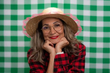 Sao Joao festivali için giyinmiş hasır şapkalı ve fotoğraf için poz veren bir kadının portresi. Yeşil ve beyaz karalanmış arkaplanda izole.