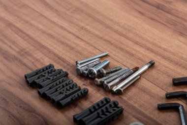 Screws, nuts, washers, L wrench, isolated on wooden background. clipart