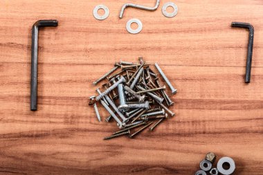 Screws, nuts, washers, L wrench, isolated on wooden background. clipart