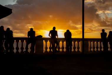 Salvador, Bahia, Brezilya - 16 Haziran 2019: İnsanlar, siluet içinde, Bahia 'nın Salvador kentindeki Porto da Barra' da günbatımının keyfini çıkarırken görüldüler..