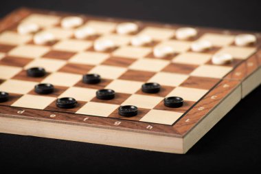 Damalı dama tahtası. Oyun konsepti. Masa oyunu. Hobi olarak. Oyun sahasında dama oynuyoruz. Siyah arkaplanda.