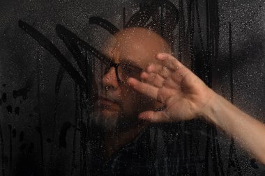 Islak cama dokunan, reçeteli gözlüklü kel adamın yakın plan portresi. Siyah arkaplanda izole.