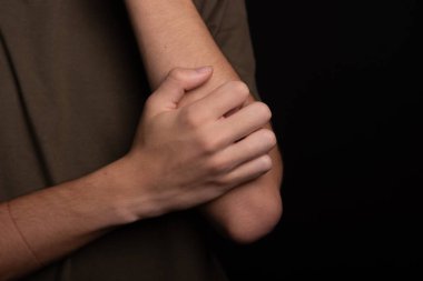 Genç adam eliyle kolunu kaşıyordu. Deri hastalığı. Kızarıklık, alerji. Siyah arkaplanda izole.
