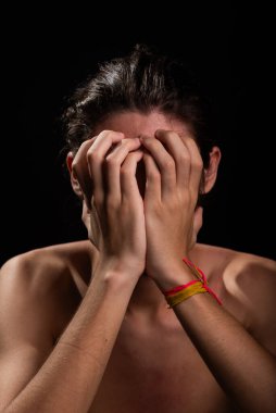 Genç bir adam, üstsüz, iki eliyle yüzünü tırmalıyor. Deri hastalığı. Kızarıklık, alerji. Siyah arkaplanda izole.