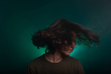 Stüdyoda el kol hareketi yapan yakışıklı bir gencin portresi. Dumanlı yeşil arkaplanda izole edilmiş.