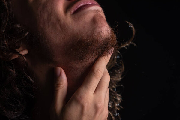 Man scratching his neck with his hand. Skin disease. Irritation, allergy. Isolated on black background.