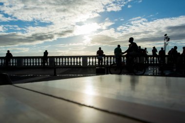 Salvador, Bahia, Brezilya - 2 Ağustos 2019: Salvador, Bahia 'da öğleden sonra Porto da Barra plajı boyunca gezen turistler ve siluet içindeki insanlar görülüyor..