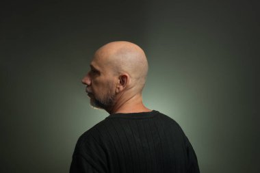 Esrarengiz, orta yaşlı, koyu renk gömlekli kel bir adam. Stüdyoda fotoğraf. Yapay dumanlı stüdyo arkaplanı.