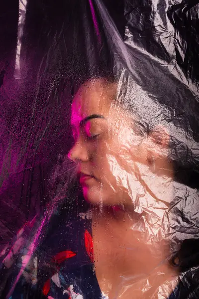 Stock image Beautiful woman behind transparent plastic feeling suffocated. Isolated on black background.