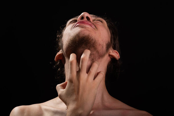 Man, shirtless, scratching his neck with one hand. Skin disease. Irritation, allergy. Isolated on black background.