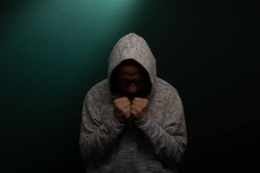 Kafası aşağıda kapüşonlu sweatshirt giyen gizemli bir adam. Koyu arkaplanda izole.