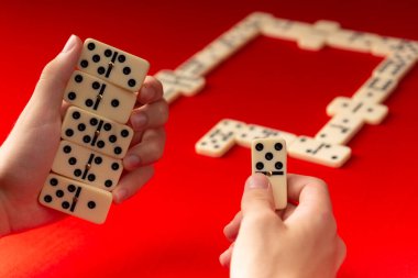 Domino oyuncularının elleri dikdörtgen sayı bloklarını tutuyor. Masa oyunu. Kırmızı arkaplan.