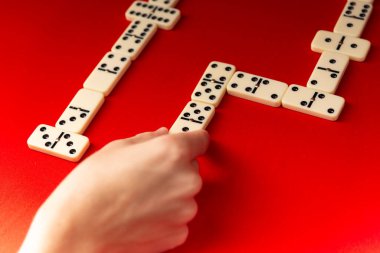 Domino oyuncuları dikdörtgen şeklinde akrilik fayanslar yerleştiriyorlar. Masa oyunu. Kırmızı arkaplan.