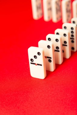 Domino etkisi başlamaya hazır. Arka arkaya akrilik parçalar. Kırmızı arkaplanda izole.