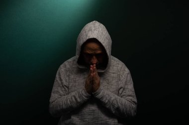 Kafası aşağıda kapüşonlu sweatshirt giyen gizemli bir adam. Koyu arkaplanda izole.