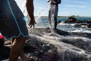 Balıkçılar, Itacare, Bahia 'da sahildeki kayalıklarda balık ağlarıyla ilgilenirken görülüyor..