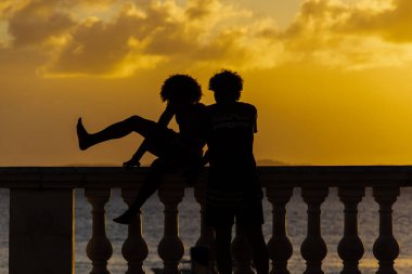 Salvador, Bahia, Brazil - June 15, 2019: Two unidentified people are seen in silhouette at Porto da Barra during sunset in the city of Salvador, Bahia. clipart