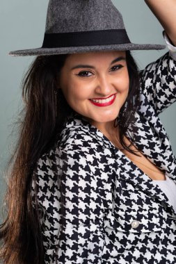 Siyah beyaz elbiseli gri şapkalı, kameraya bakan güzel bir kadının portresi. Açık yeşil arkaplanda izole.