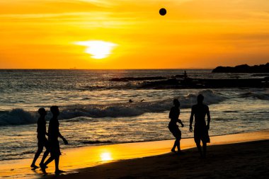 Salvador, Bahia, Brezilya - 06 Aralık 2019: İnsanlar Farol da Barra plajının kenarında gün batımında plaj futbolu oynarken görülüyor. Salvador, Bahia.